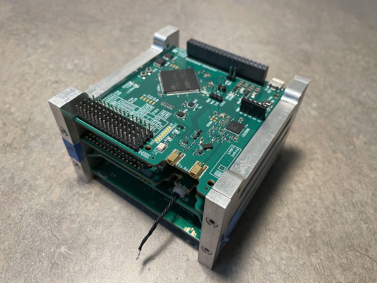 CubeSat avionics stack in an aluminum frame showing multiple PCBAs