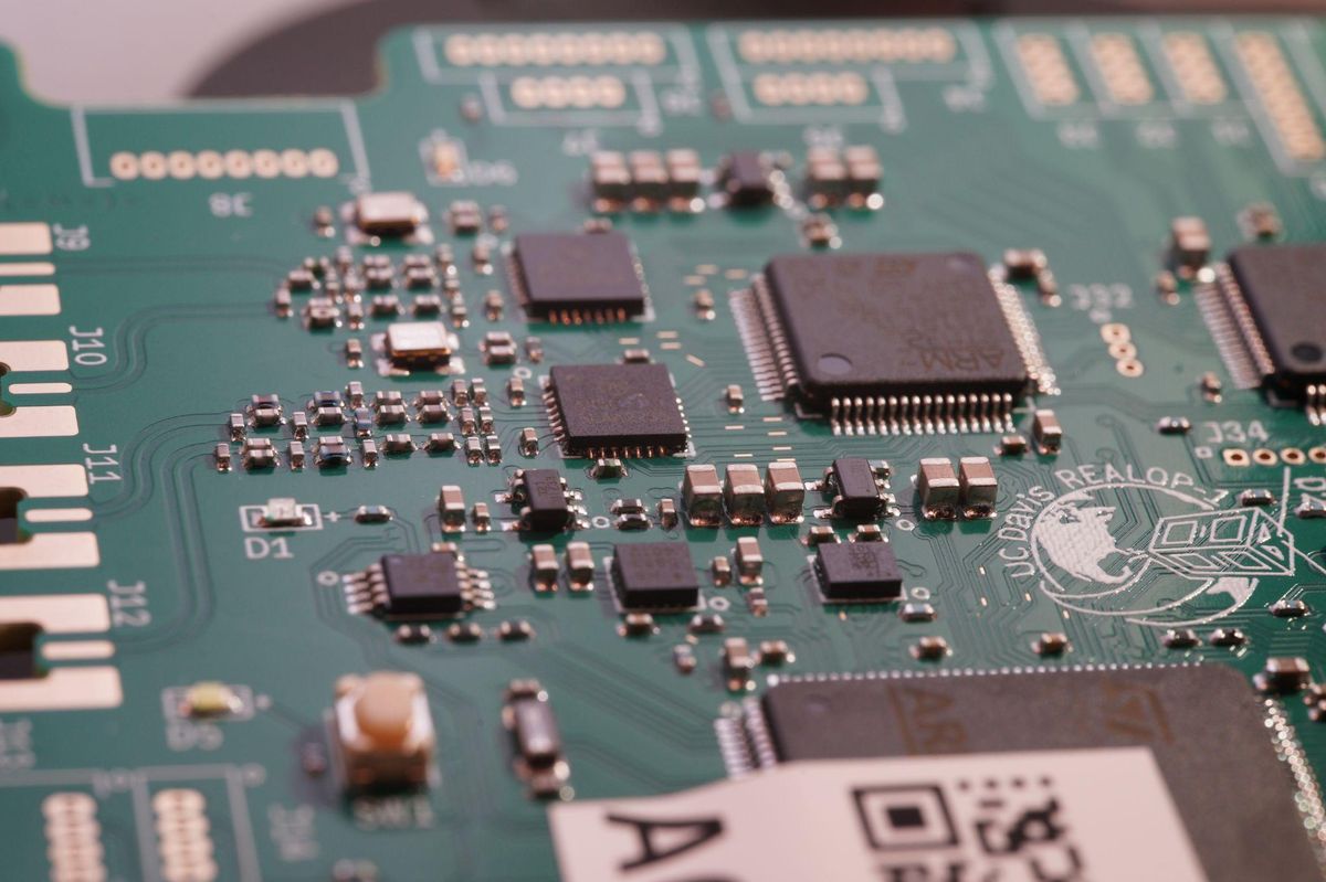 Close-up photo of a flight computer board focusing on the RF subsystem and the REALOP-1 logo